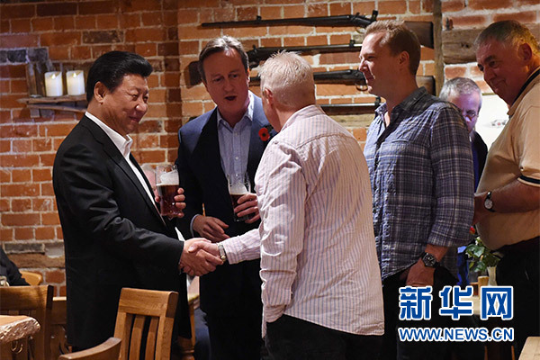 這是習近平與卡梅倫飲啤酒，并同當?shù)孛癖娊徽?。新華社記者 饒愛民 攝